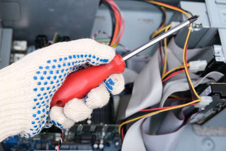 A hand of a technician repairer holding a screwdriver in order to upgrade or repair a broken home...