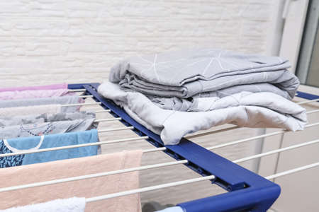 Fresh washed bed linen stacked, piled on a dryer, dry apparel on a folding portable close up, housekeeping, homework and chores concept.の写真素材