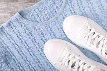 Blue pastel warm pullover for cold autumn and winter weather with white casual leather sneakers on...