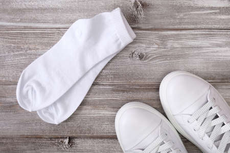 White leather sneakers and white cotton socks on wooden background, a set for walking and workout.の写真素材