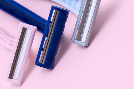 Disposable plastic razor blades for everyday morning routine and shaving unwanted hair on face, legs and armpits, grooming concept on pink backgroundの写真素材