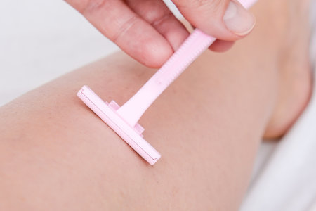 Woman shaving legs with pink disposable plastic razor blade, unwanted hair removalの写真素材