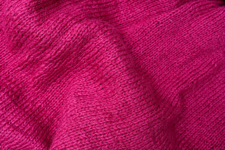 The texture of cotton folded knitted fabric, bright crumpled pink woolen knitwear textile background
