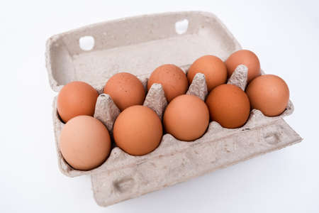 Brown eggs in recycled carton pressed box container on white table