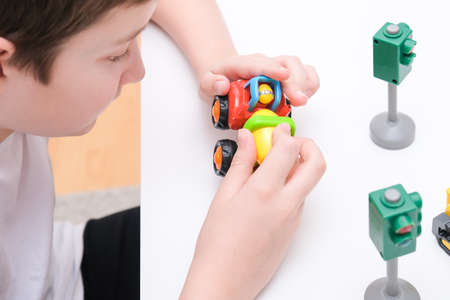 A boy playing toy cars on a white table