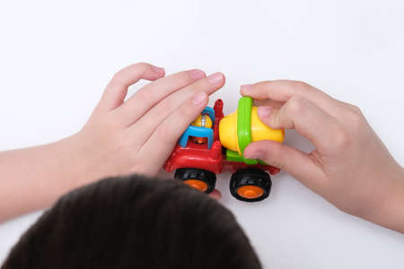 A boy playing toy cars on a white table