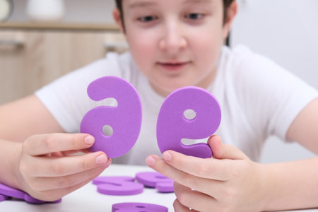 A boy learning math, count exercises at home, holding colorful foam numbers in handの写真素材