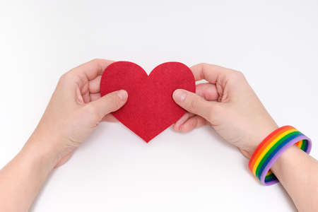 A woman wearing lgbtq rainbow bracelet holding a heartの写真素材