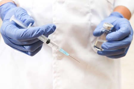 Fight against covid-19, doctor holding syringe and vial with vaccine, vaccination conceptの写真素材