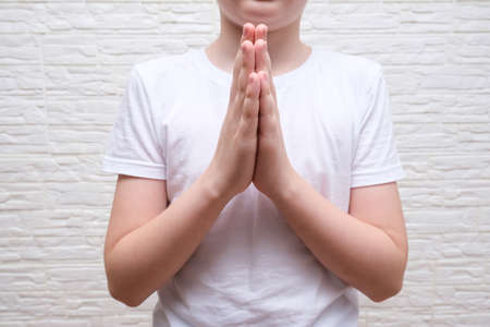 A boy showing gratitude gesture on white background, he is hopeful while prayingの写真素材