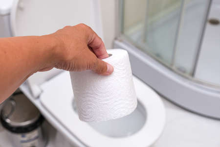 A hand holding a white roll of toilet paper, stomach abdomonal pain and digestive problems conceptの写真素材
