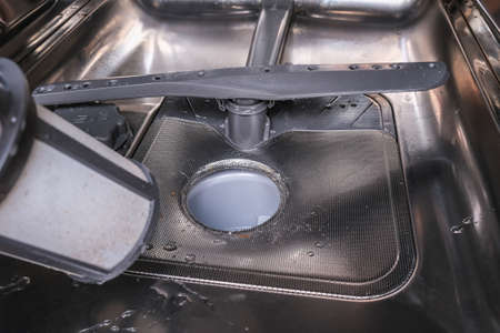 A hand taking out dishwasher filter to clean it, dis washer cleaning concept, kitchen home appliances care and maintenanceの写真素材