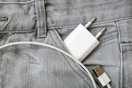 Usb charger, wire and adapter plug in grey jeans pocket, dont forget charger at homeの写真素材