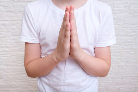 A boy showing gratitude gesture on white background, he is hopeful while prayingの写真素材