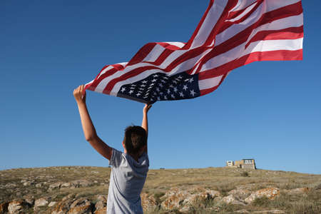 A boy holding waving US flag, beeng a patriot conceptの写真素材