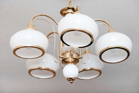 Classic candelier italian style hanging on a ceiling, lamp with 5 white lights and golden metal...