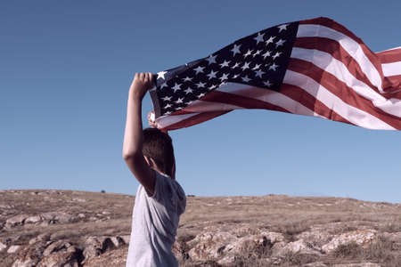 A boy holding waving US flag, beeng a patriot conceptの写真素材