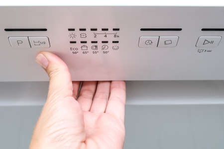 Woman hand opening washing machine in the middle if a washing cycle in order to check proper work of...
