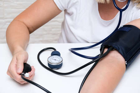 Woman measuring blood pressure by herself at home, pressure control to prevent heart cardiolvascular problems of people with high risk.の写真素材