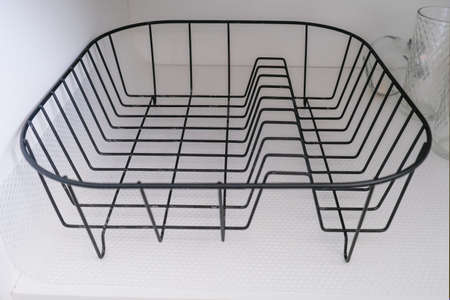 Removable empty steel dish dryer rack in a kitchen cupboard, modern convenient useful equipment for drying tableware and kitchen utencils after washingの写真素材