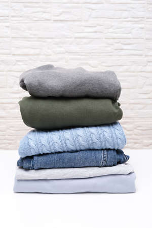 Vertical image of folded stacked warm winter and autumn casual clothes close upの写真素材