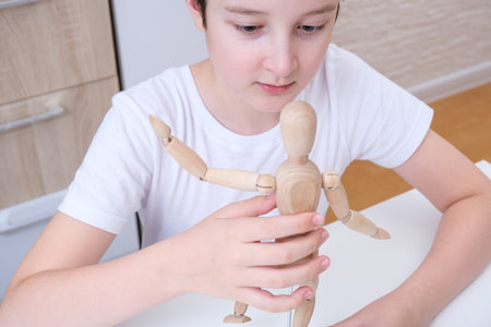 A boy playing wooden mannequin, articulated doll at home, kid, child trying different poses and roles of peopleの写真素材