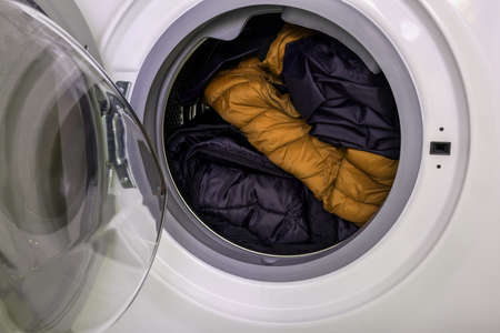 Dirty clothes of different colors in a washing machine drum, laundry concept.の写真素材