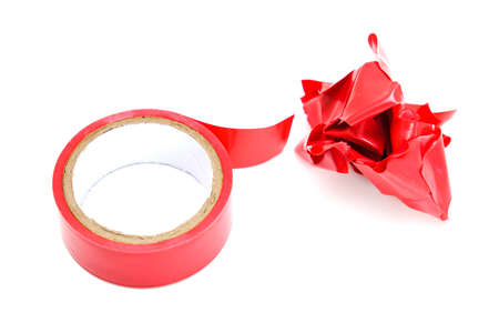 Red roll and a lump of crumpled used electrical sticky isolation duct tape on white background.の写真素材