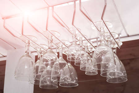 Clear wine glasses hanging in a row over bar rackの写真素材