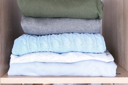 A stack of organized clothes on a shelf in a wardrobe
