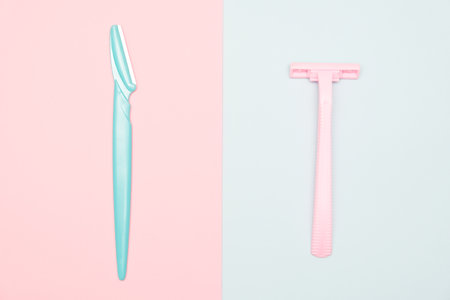 Two disposable razor blades of different colors for removing, shaving unwanted hair on face and body on blue and pink backgroundの写真素材