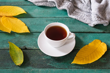 Cozy autumn fall composition with yellow leaves and a cup of coffee with a warm cozy knitted pulloverの写真素材