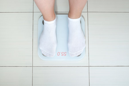 A single person standing on a weight scale, emphasizing the importance of health and fitness awarenessの写真素材