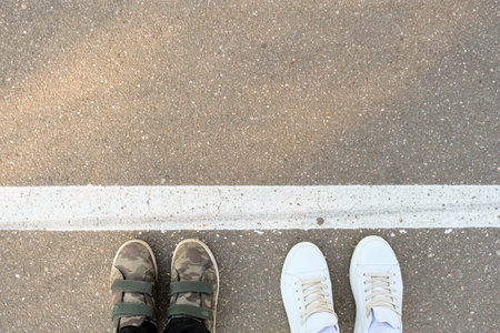 Two persons feet on a white line on the road. The line is a boundary between two lanes of trafficの写真素材