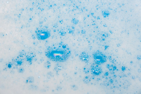 Bubbles of washing detergent foam in basin close up.