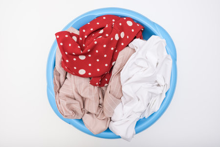 A pile of dirty laundry in a basin on white backgroundの写真素材