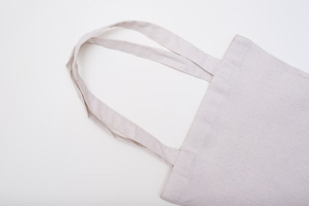 This image features a closeup view of a stylish white tote bag, complete with a handle, placed...
