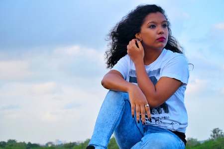 Young Indian girl in casual dress sitting near mountain