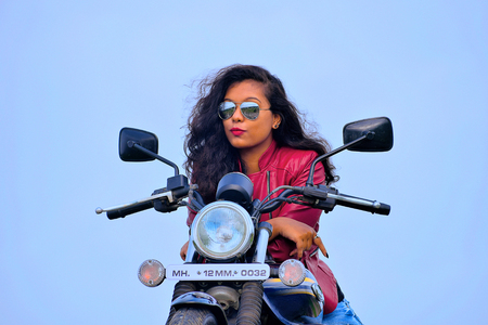 Young Indian girl posing on motorcycle, Pune