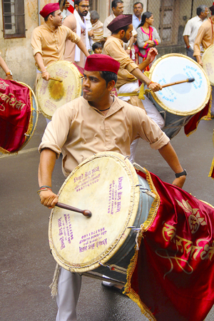 Young Indian man, dressed traditionally playing dhol-taasha during Ganapti Visarjanのeditorial素材