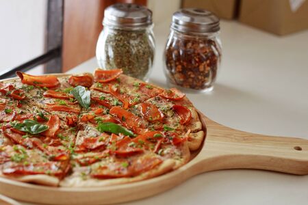 Close up of sliced carrots sprinkled with herbs and on a jowar base pizza served in a wooden plateの写真素材
