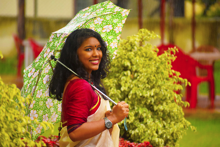 Indian girl In sari walking in the rain with umbrella at Pune, Maharashtraの写真素材