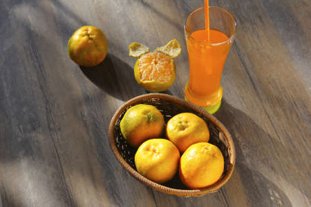 Fresh orange fruits with glass of orange juice isolated on wooden background