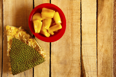 Top view of red bowl with jackfruit pods and jackfruit skin isolated on wooden backgroundの写真素材
