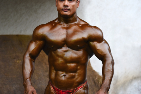 Young bodybuilder showing chest and biceps muscles. Front pose, Indian Body Builders Association show, Balewadi, Baner, Pune, Maharashtra, Indiaのeditorial素材