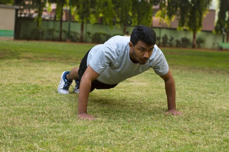 Young and handsome guy doing push ups in a park