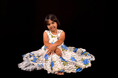 Little girl with a cute smile looking at camera against a black backdrop, Pune, Maharashtraの写真素材