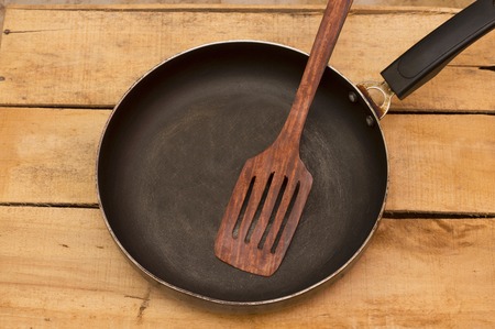 Empty frying pan and spatula overhead view on the wood backgroundの写真素材