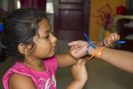 Indian baby girl tying a friendship band to her friend at Puneの写真素材
