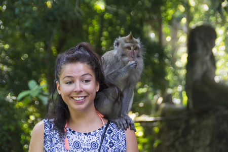INDONESIA, BALI, May 2016, Tourist with crab-eating macaque sitting on her shoulderのeditorial素材